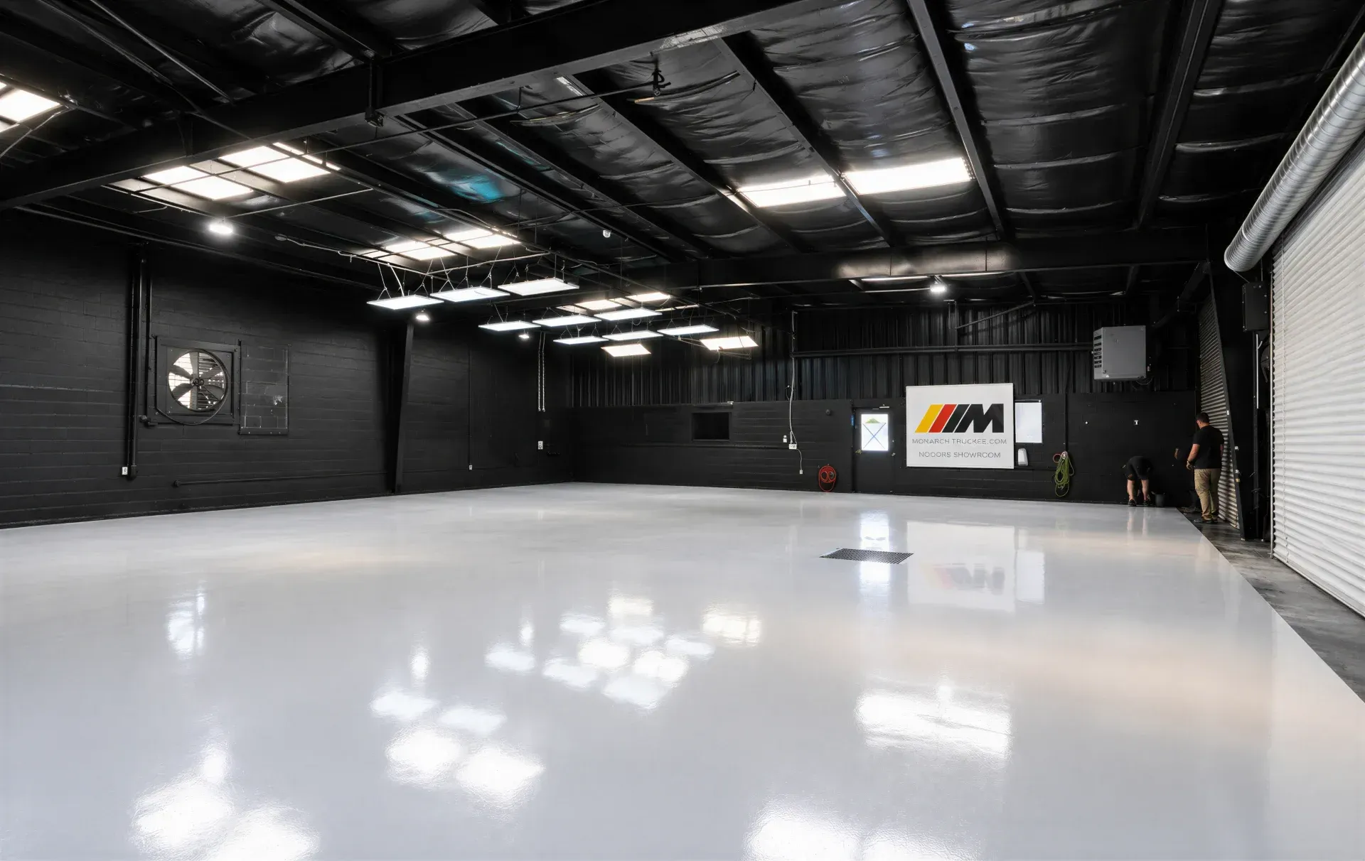 Large room with glossy brown-and-black floor, white walls, and black railings surrounding the space.