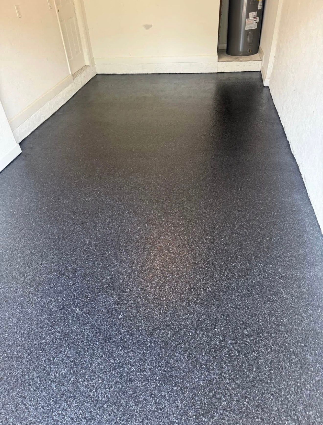 Empty hallway with dark speckled flooring and white walls