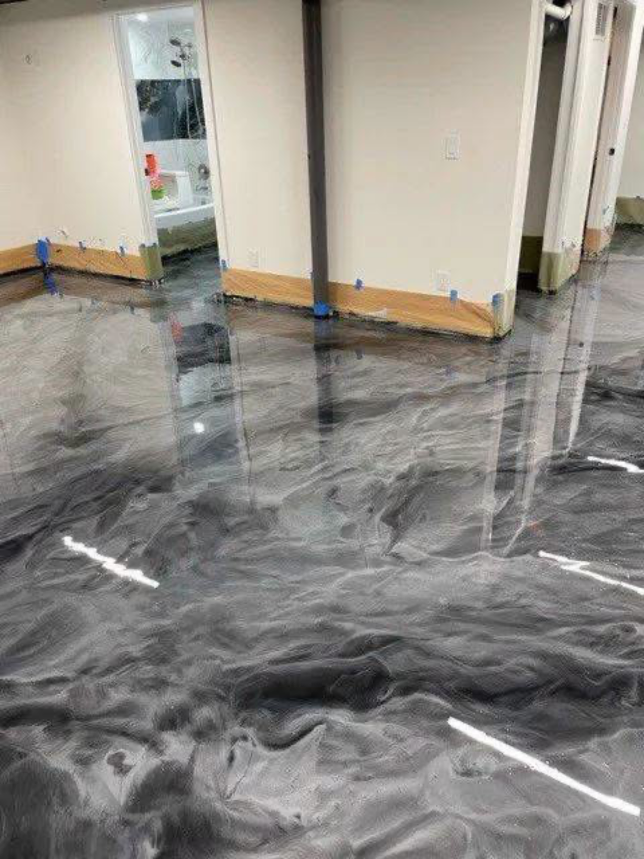 Man spreading epoxy on a glossy garage floor in a modern home garage