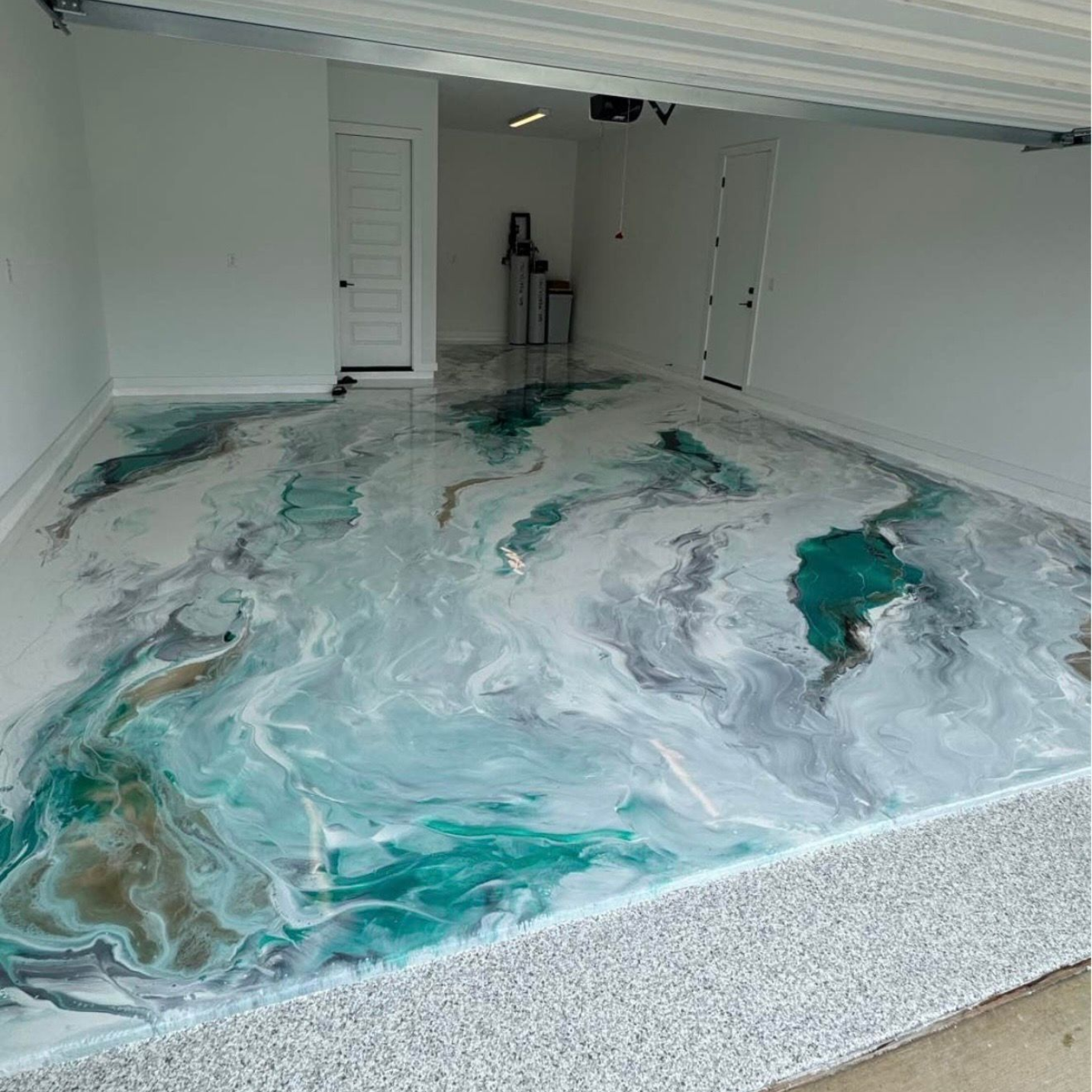 Turquoise and white marbled epoxy floor in a garage with an open door