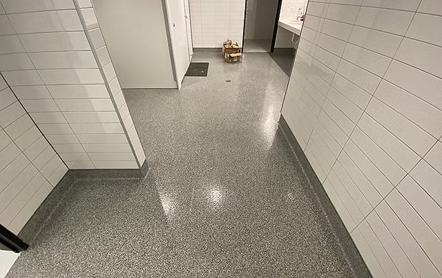 Empty tiled hallway with a small cardboard box near the far wall.