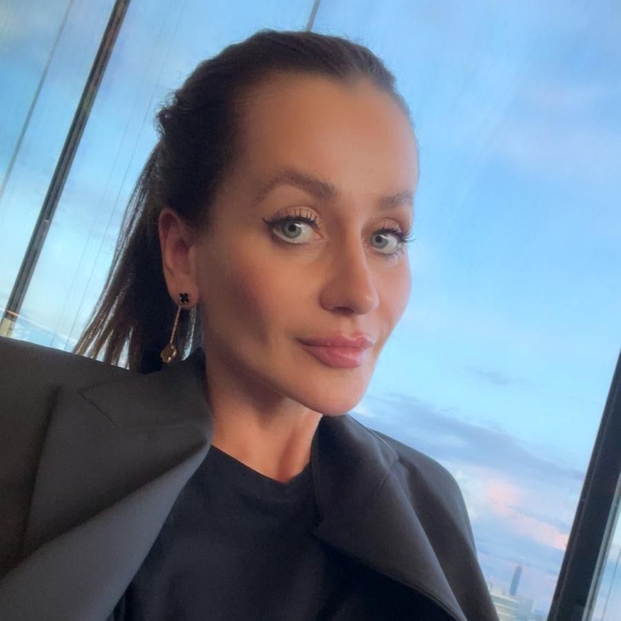 Frau in schwarzer Jacke macht ein Selfie am Fenster bei Sonnenuntergang