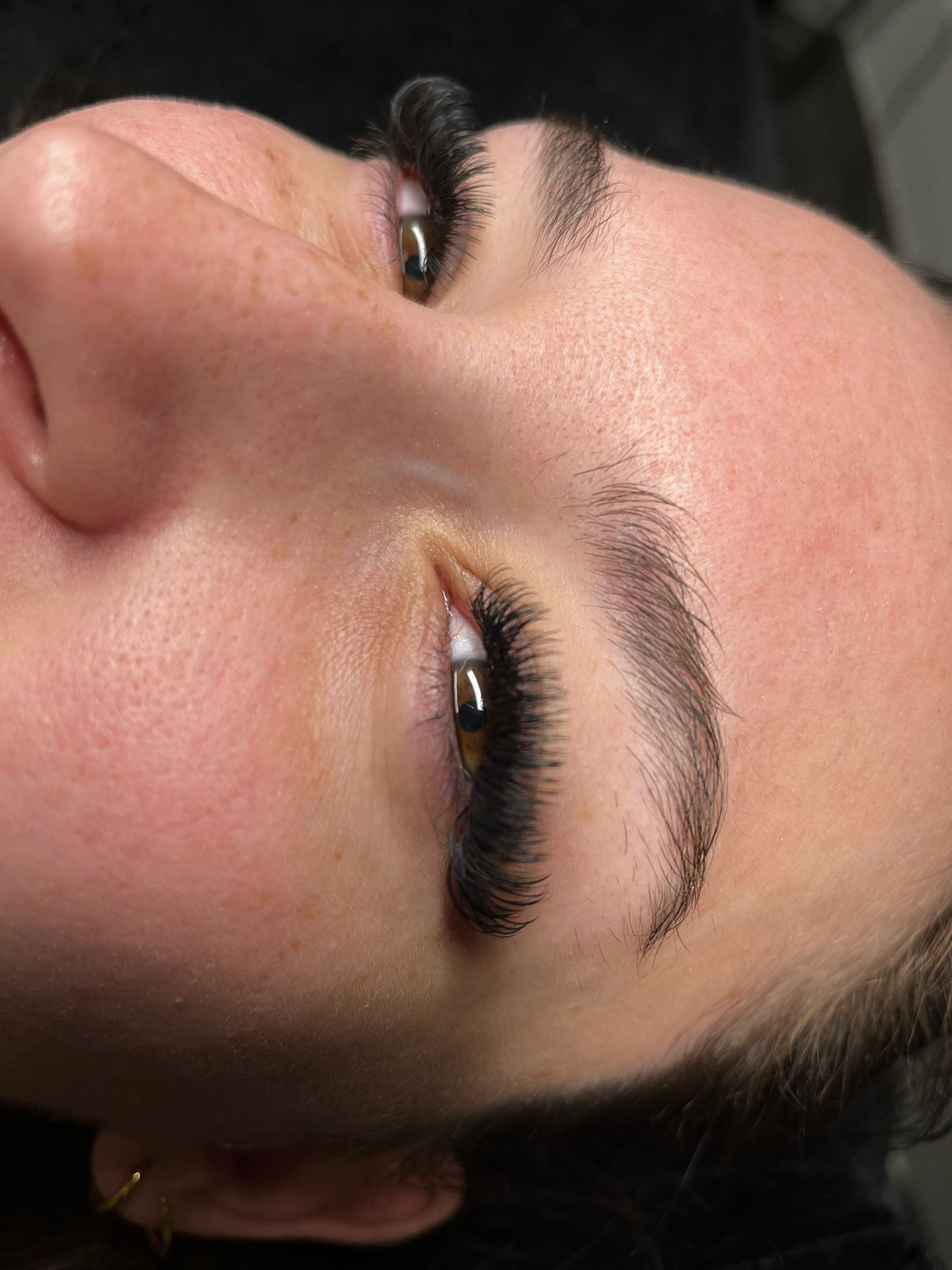 Nahaufnahme eines Gesichts mit geschlossenen Augen, auf dem lange, dunkle Wimpern und gepflegte Augenbrauen zu sehen sind.