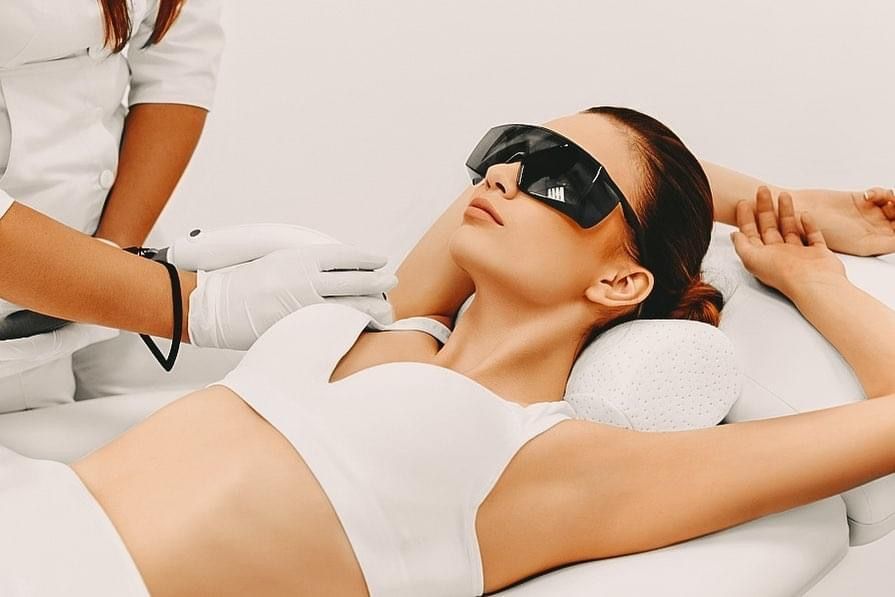 Eine Person mit schwarzer Schutzbrille liegt während einer Schönheitsbehandlung auf einer Spa-Liege.