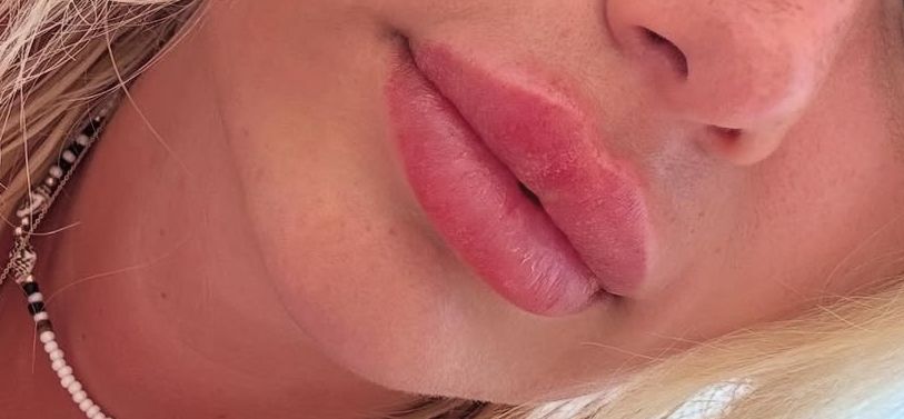 Nahaufnahme der Lippen und des unteren Gesichts einer Person mit rosa Lippenstift, die eine Halskette trägt