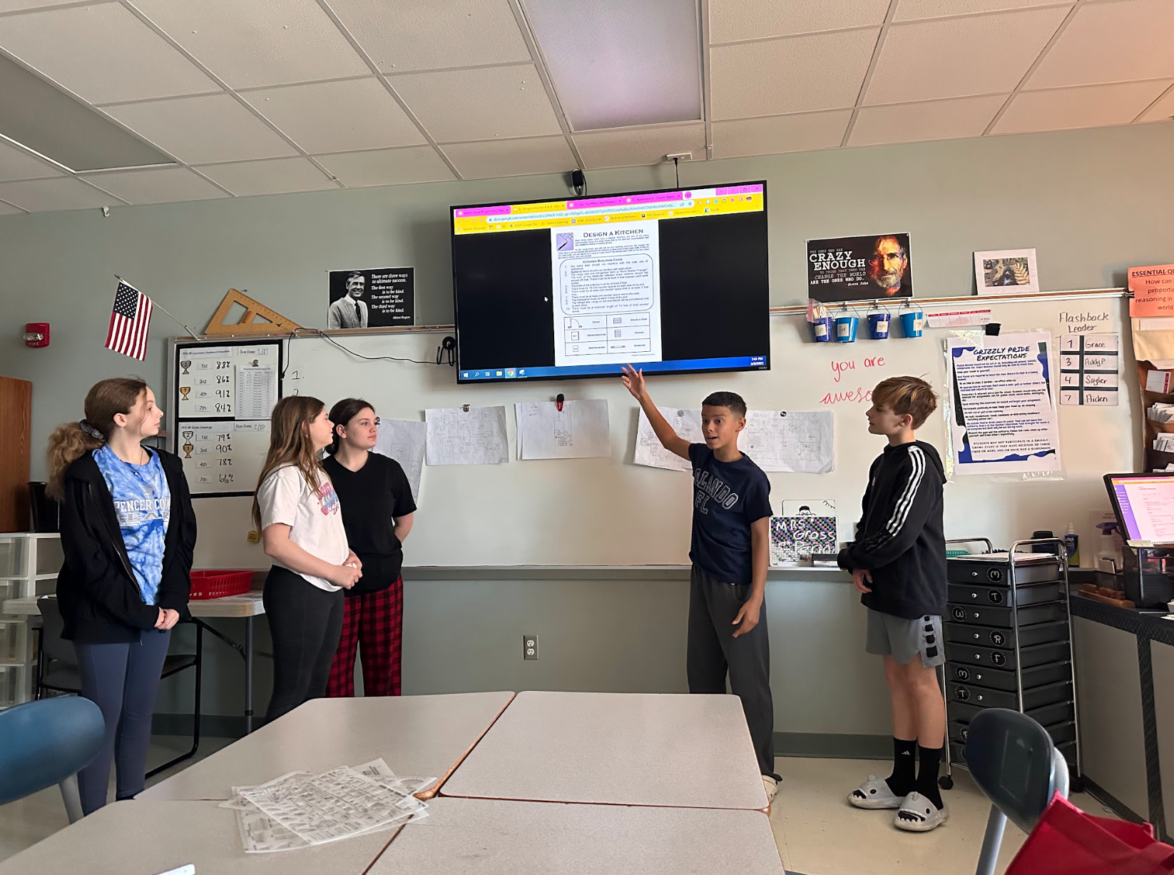 A group of students are standing in front of a large screen in a classroom.