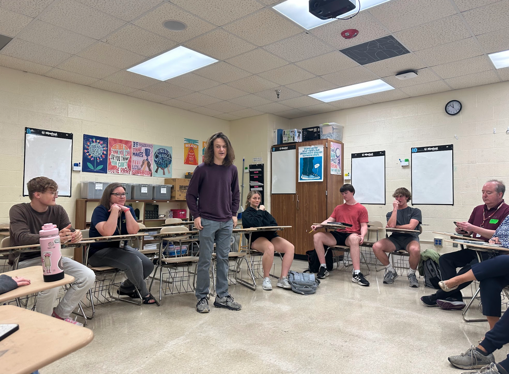 A group of people are sitting at desks in a classroom.