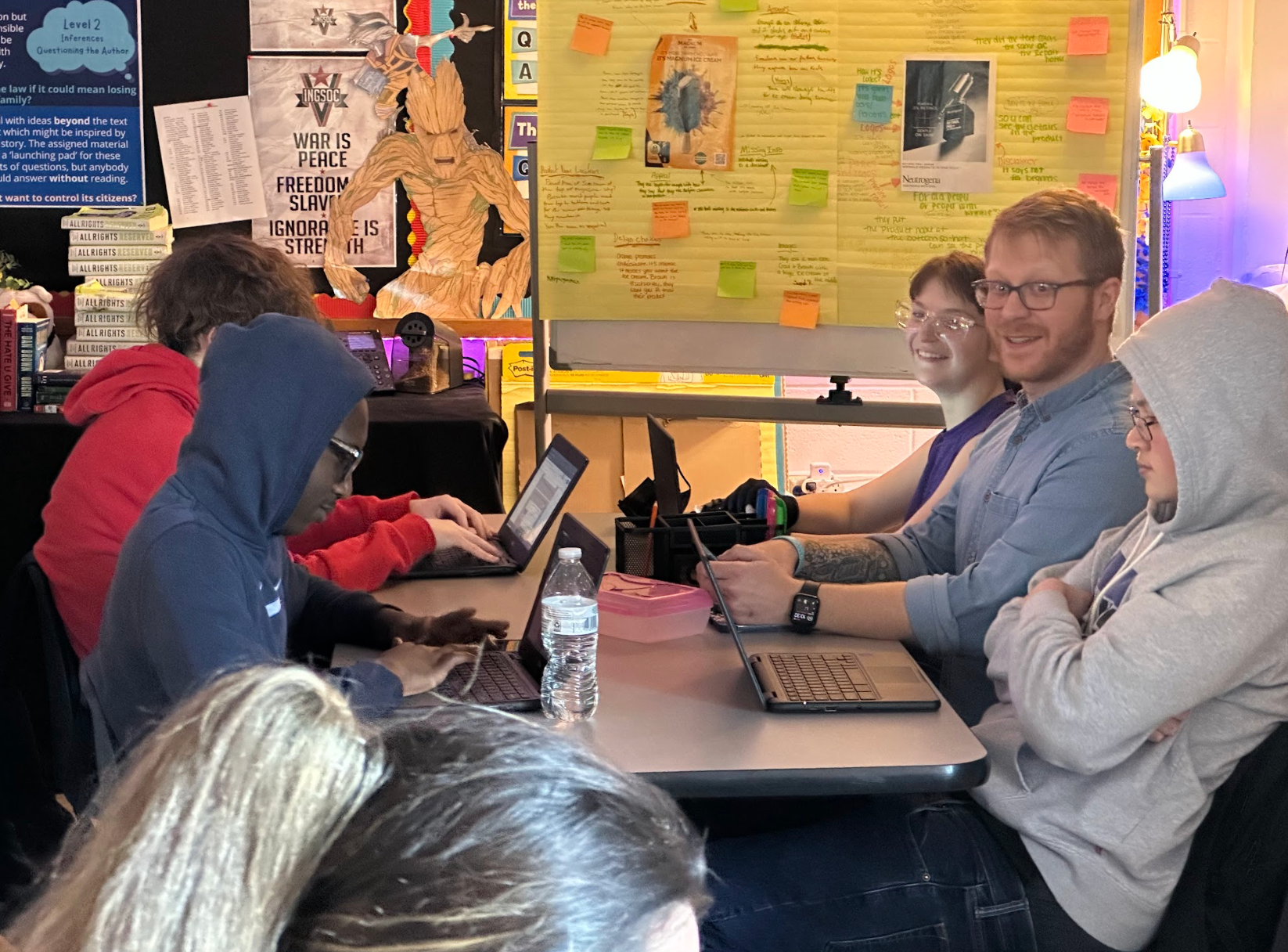 A group of people are sitting around a table with laptops.