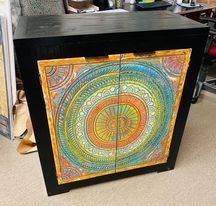 Black cabinet with colorful mandala-style double doors in a store setting