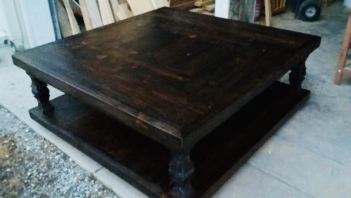 Dark wooden low square table with carved legs in a workshop setting