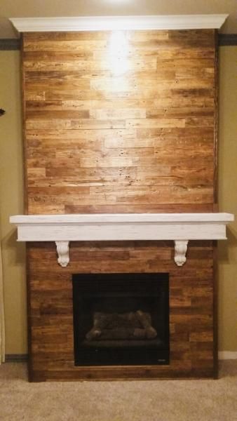 Brick fireplace with white mantel and wood-paneled chimney breast in a room