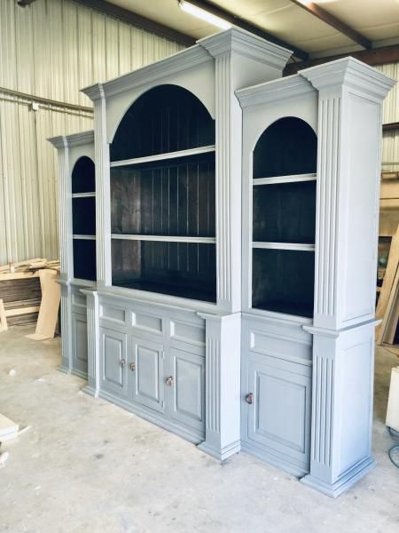 Gray built-in cabinet and shelving unit with arched openings in a workshop setting