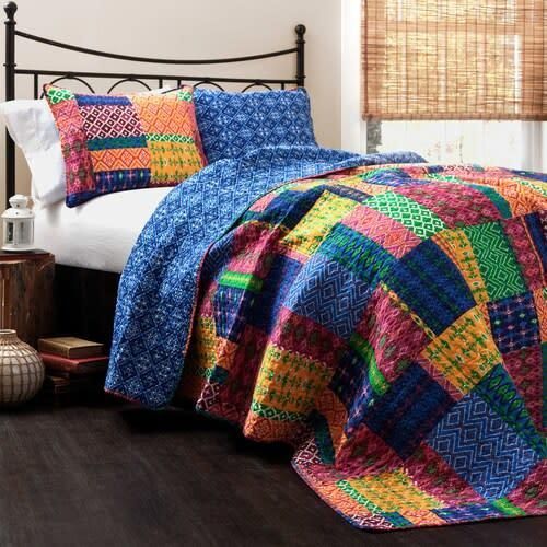 Colorful patchwork quilt on a bed with blue pillows and a black metal headboard