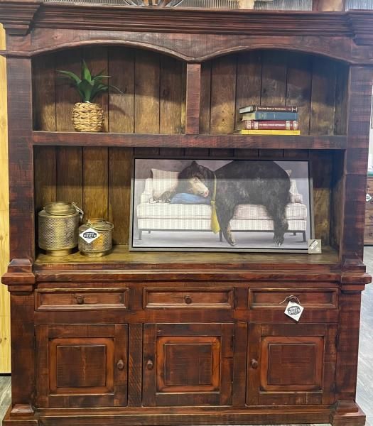 Wooden hutch with shelves, decor, and a black-and-white cow figurine behind glass in the center.
