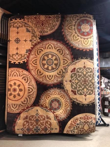 Decorative wall hanging with ornate circular mandala patterns in tan, brown, black, and gold.