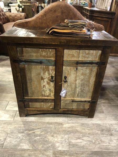 Rustic wooden cabinet with two doors and a decorative curved top, standing on a tiled floor.