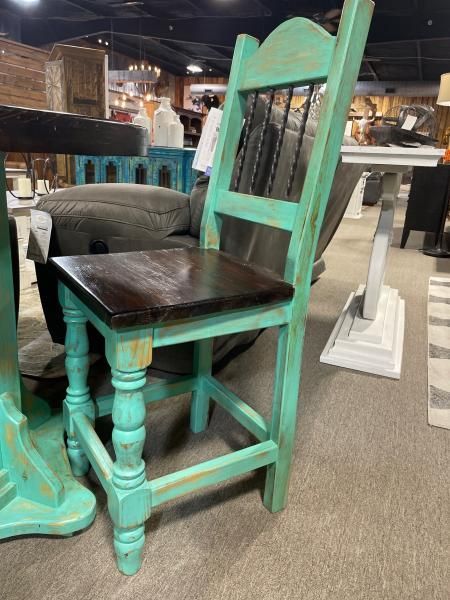 Turquoise distressed wooden chair with black seat in an antique store.