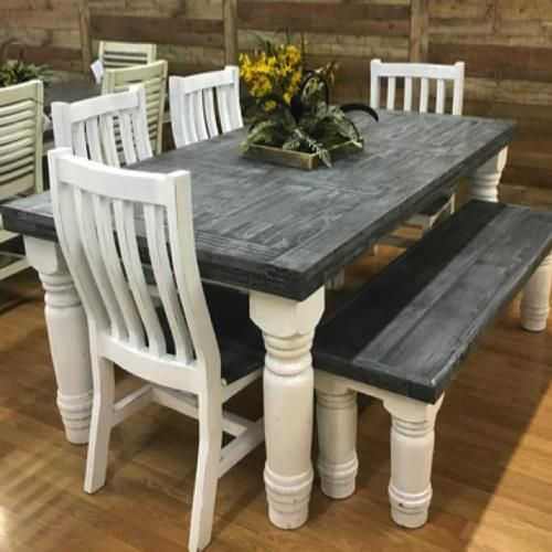 Rustic dining table with gray top, white chairs, and matching bench in a wood-floored room