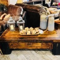 Rustic coffee table with lanterns, candle jars, decor pillows, and dice in a cozy living room