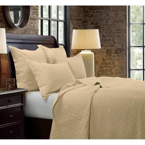 Beige bedding on a dark wood bed in a cozy bedroom with stone walls and tall windows