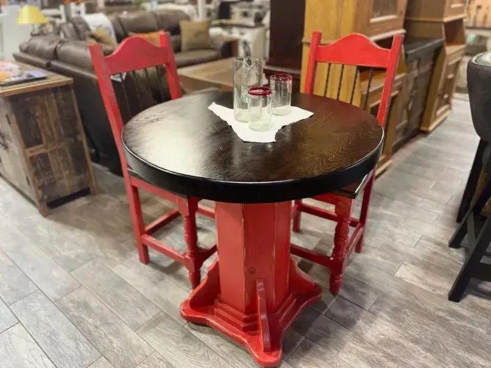 Red round café table with red chairs in a furniture store.