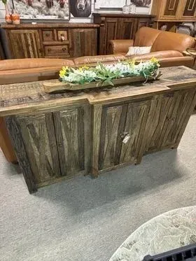 Rustic wooden console table with a floral centerpiece in a furnished living room