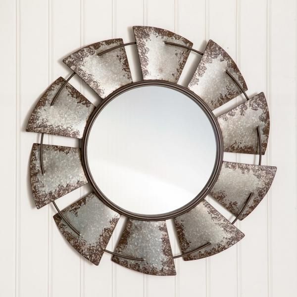 Decorative round wall mirror with rustic metal sunburst frame on a white paneled wall
