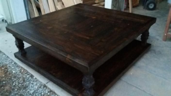 Dark wooden square coffee table with a lower shelf, shown in a workshop or garage setting.