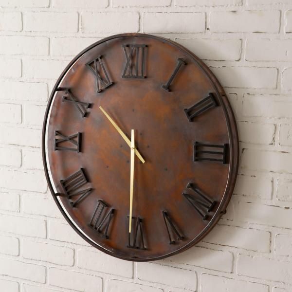 Round rustic wall clock with Roman numerals on a white brick wall.