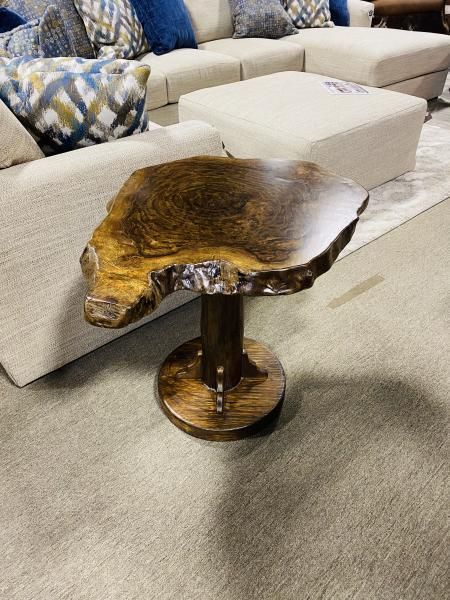 Rustic wooden side table with a live-edge top in a beige living room.