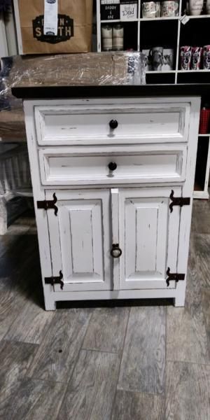 White distressed farmhouse cabinet with two drawers and double doors, topped with a countertop on a tiled floor.