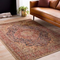 Vintage patterned rug on a light wood floor beside a leather sofa and potted plant