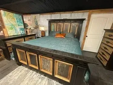 Stylish bedroom with a large bed, teal bedding, dark wood furniture, and colorful wall art