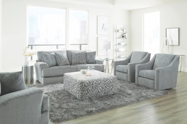 Bright living room with gray sofa, armchairs, shag rug, and white decor near large windows