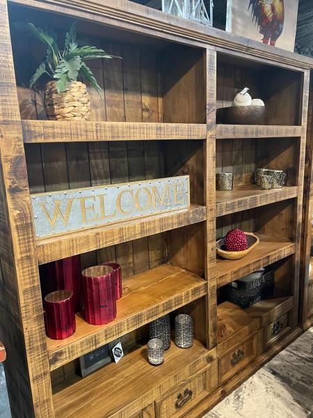 Wooden shelf display with a “WELCOME” sign, small plants, candles, and decor items.