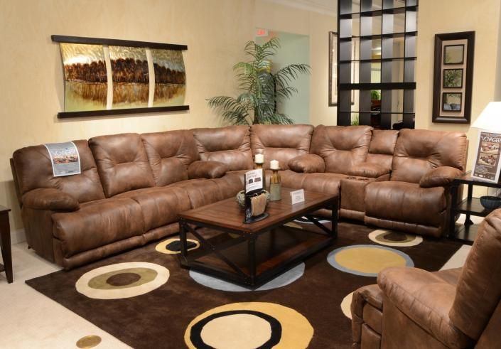 Cozy living room with brown sectional sofas, patterned rug, coffee table, and wall art