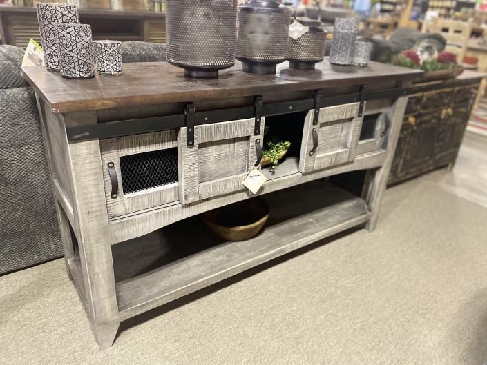 Rustic gray wooden kitchen island with open shelves and woven basket drawers, styled with decor on top