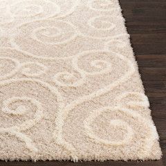 Close-up of a beige shag rug with subtle swirling pattern on a dark wood floor