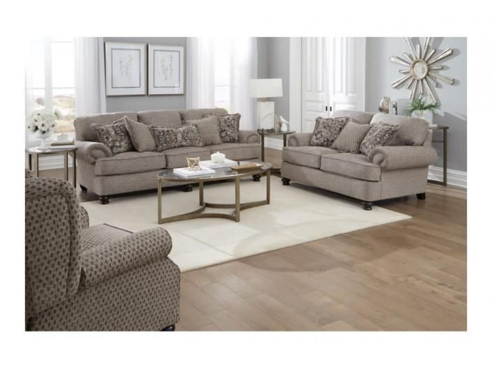 Bright modern living room with beige sofas, armchair, glass coffee table, and large windows
