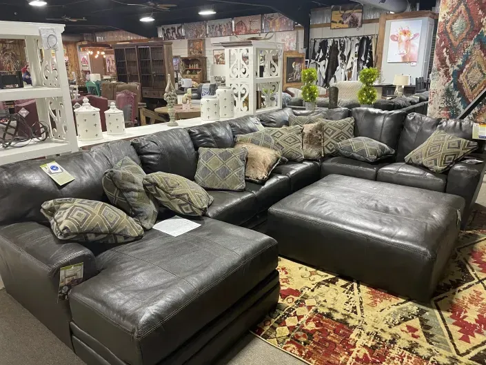 Leather sectional sofa set with patterned pillows in a furniture showroom