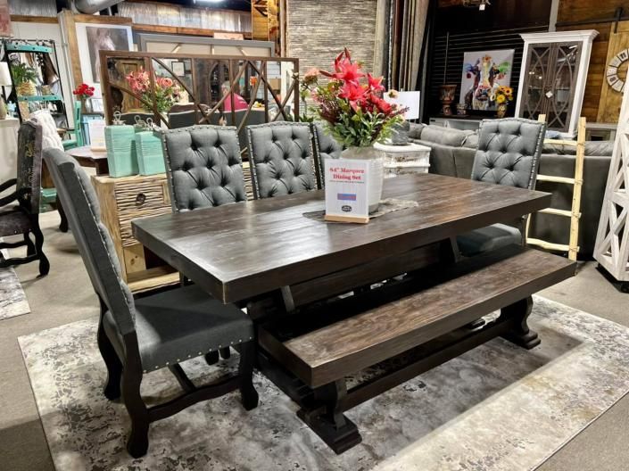 Rustic dining table set with tufted gray chairs in a furniture showroom