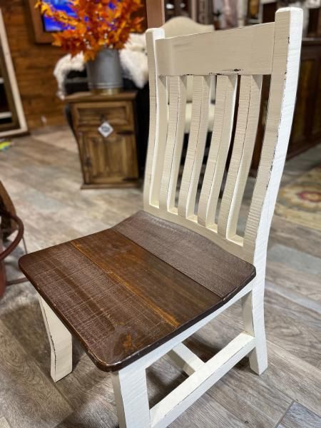 White wooden chair with dark brown seat in a rustic indoor setting