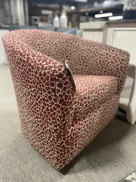 Pink patterned accent chair with curved back and armrests in a furniture showroom
