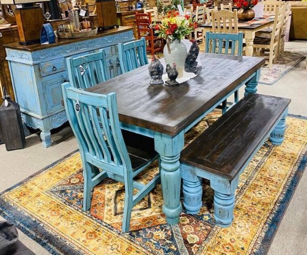Blue distressed dining table set on a patterned rug in a furniture showroom