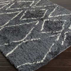 Gray shag area rug with white geometric pattern on a dark wood floor
