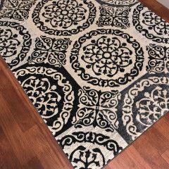 Black and cream patterned rug on a hardwood floor corner