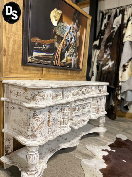 White ornate vintage dresser in a rustic room with a cowhide rug and western wall art