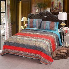 A cozy bedroom with a dark carved bed dressed in colorful striped bedding and matching pillows