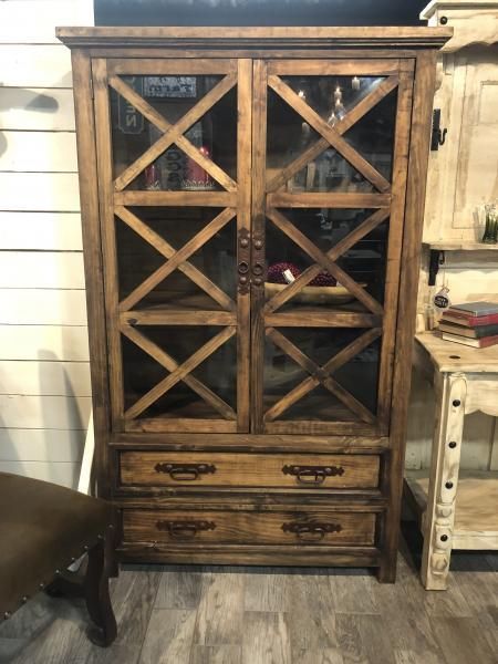 Wooden wine cabinet with glass doors and drawers in a rustic room