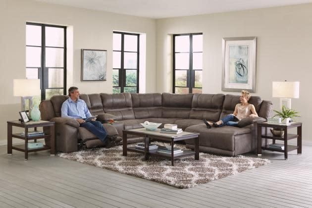 Modern living room with an L-shaped sectional, coffee table, lamps, and two people seated apart